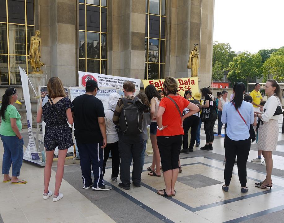 Turisti čitaju materijale o Falun Gongu i progonu u Kini.