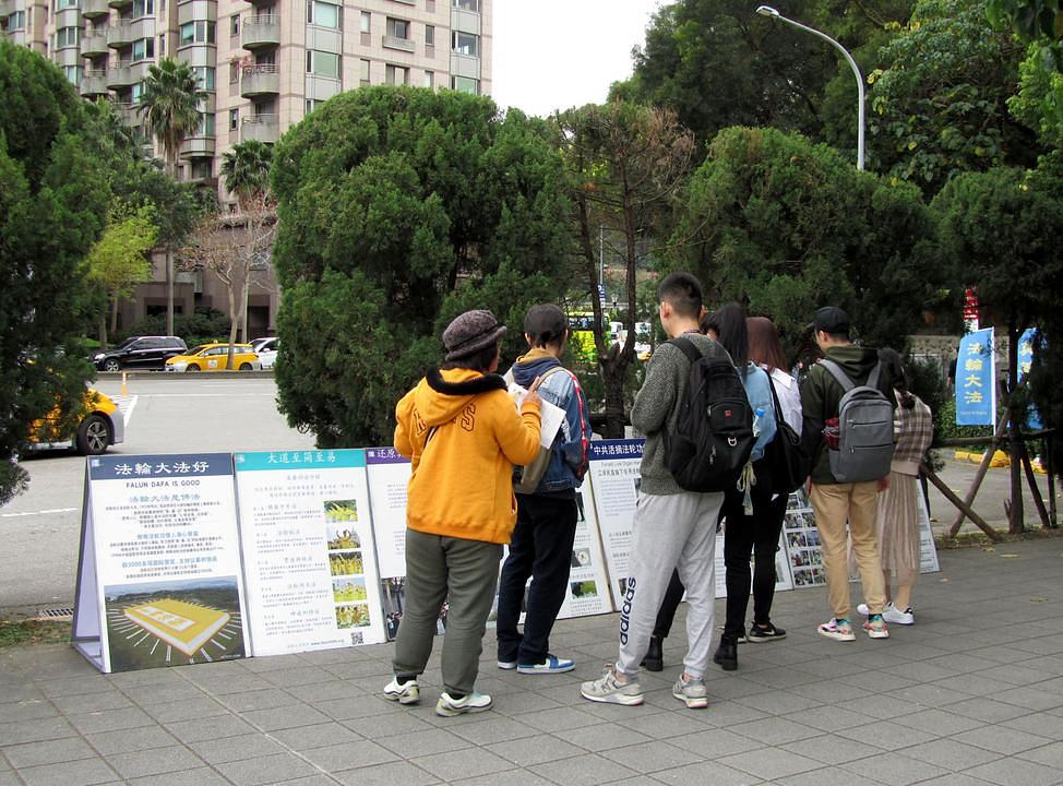 Kineski turisti čitaju informacije o Falun Gongu i o progonu.