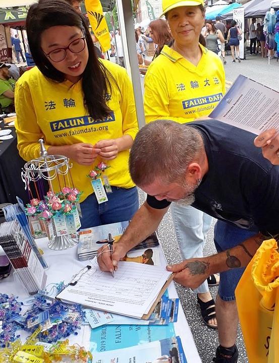 Posjetitelj potpisuje peticiju kojom se poziva na okončanje progona Falun Gonga koji vrši KPK.