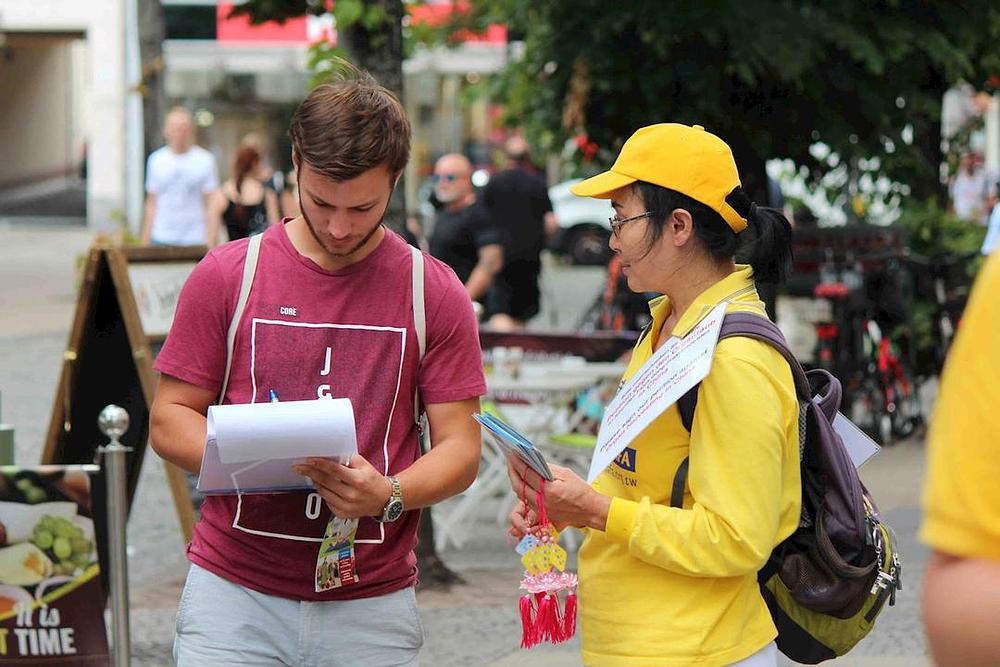 Pješaci razgovaraju sa praktikantima kako bi saznali više o Falun Gongu i potpisali peticiju koja poziva na okončanje progona u Kini.