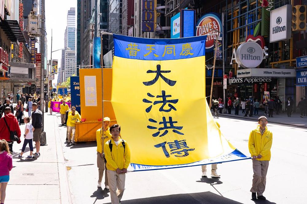 Na transparentu piše: "Dafa je prihvaćena širom svijeta, slavimo zajedno"