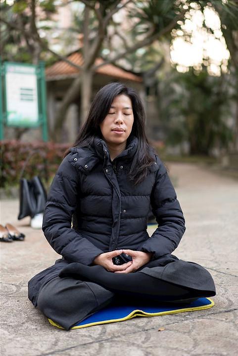 Gospođa Chen u parku radi petu Falun Dafa vježbu, sjedeću meditaciju.
