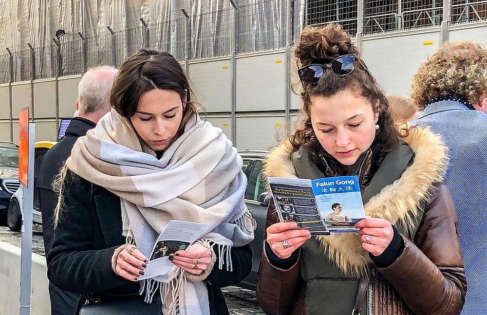 Dvije turistkinje iz Francuske čitaju Falun Gong letke.