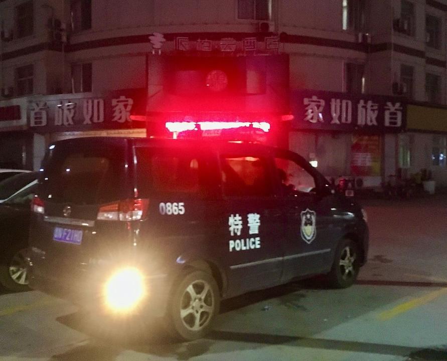 Policijsko vozilo ispred hotela „Paibaiyun“ i osoblje koje dezinficira ulaz