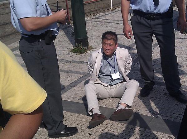  Kineski službenik  kojem je češka policija stavila lisice sjedi na zemlji. Njegova oznaka s imenom, obrnuta na ovoj slici, pokazuje da radi u Kineskom veleposlanstvu u Pragu