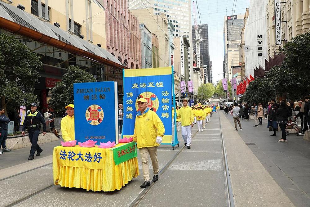 Približno 500 praktikanata sudjelovalo u paradi održanoj u središnjem poslovnom distriktu Melbournea 11. oktobra 2019. da bi ljudima pokazali koliko je Falun Dafa čudesan. Praktikanti guraju veliki model knjige „*Zhuan Falun*“.
