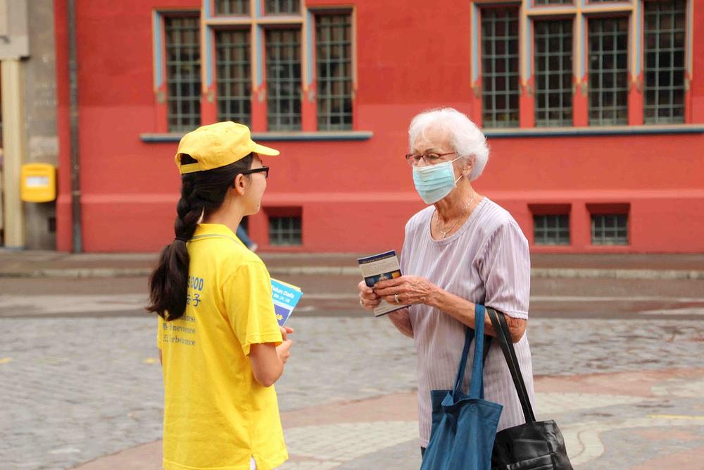 Prolaznici na Marktplatzu u Bazelu se zaustavljaju da bi saznali više o Falun Dafa.