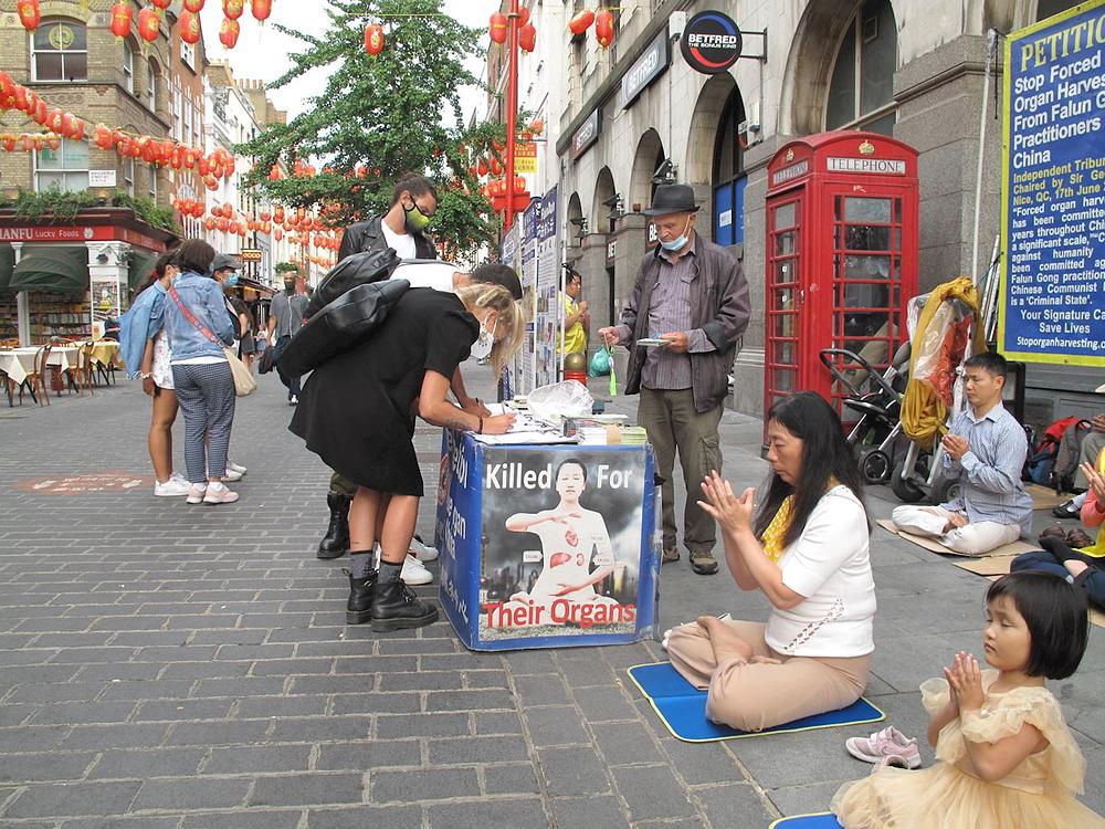 Prolaznici saznaju za progon u Kini i potpisuju peticiju kako bi se progon zaustavio.