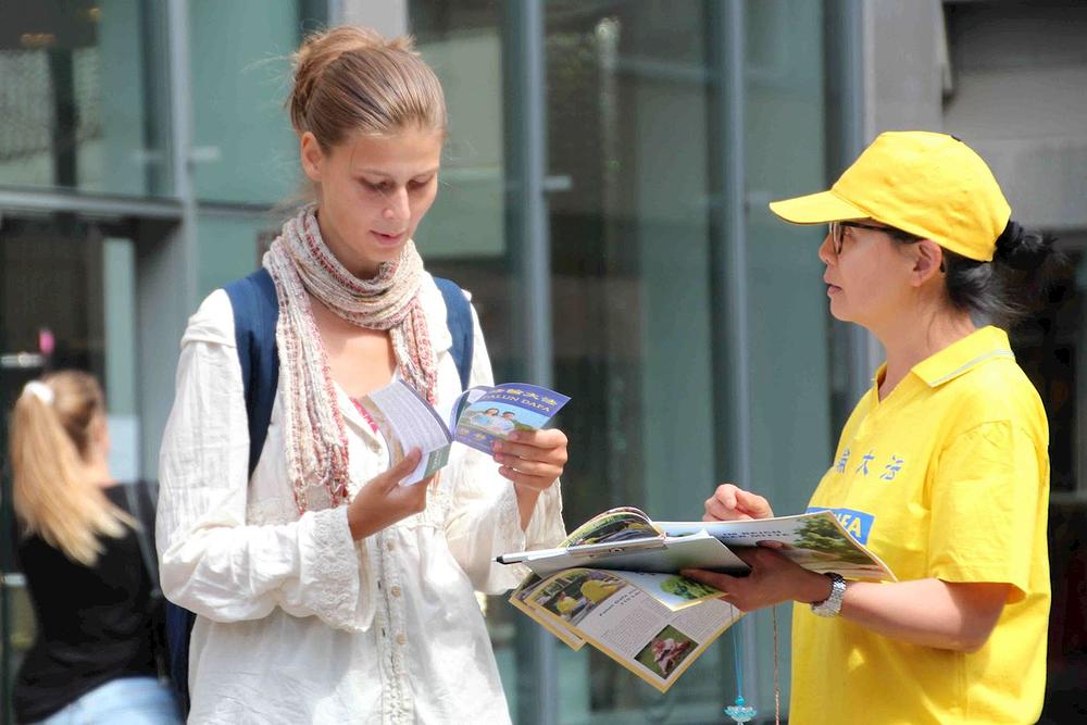 Prolaznici uzimaju pamflete kako bi više saznali o Falun Dafa.
 
