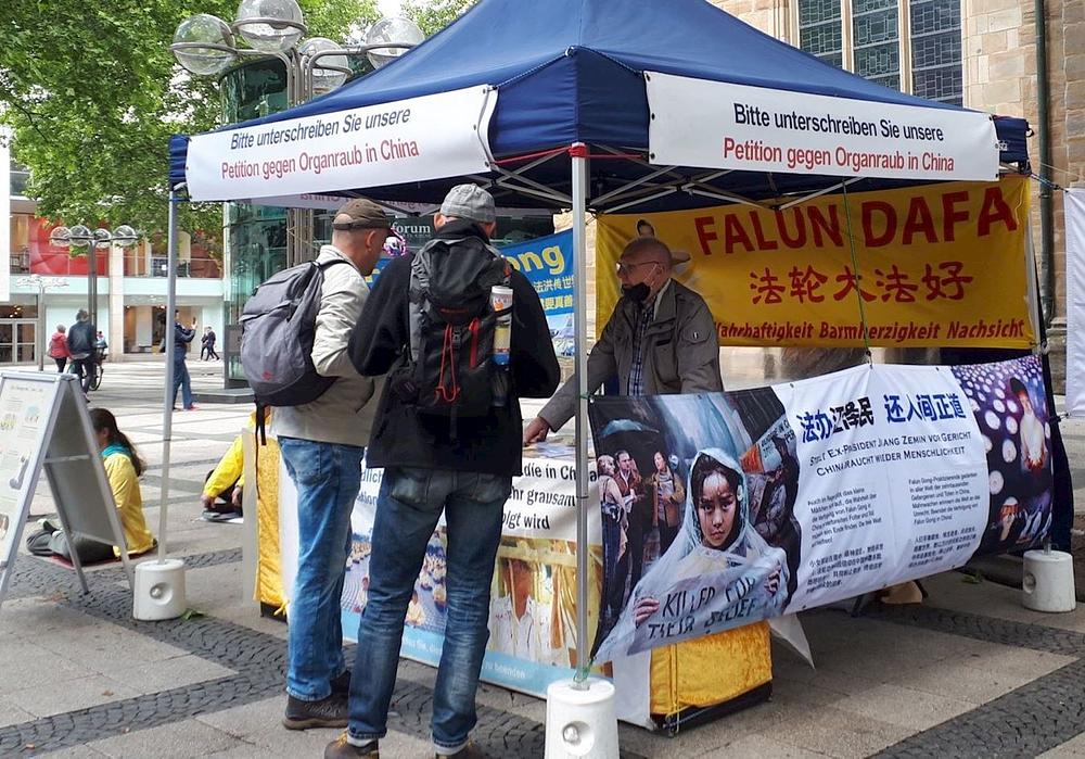 Ljudi se zaustavljaju kraj štanda kako bi saznali više o Falun Dafa i progonu u Kini.