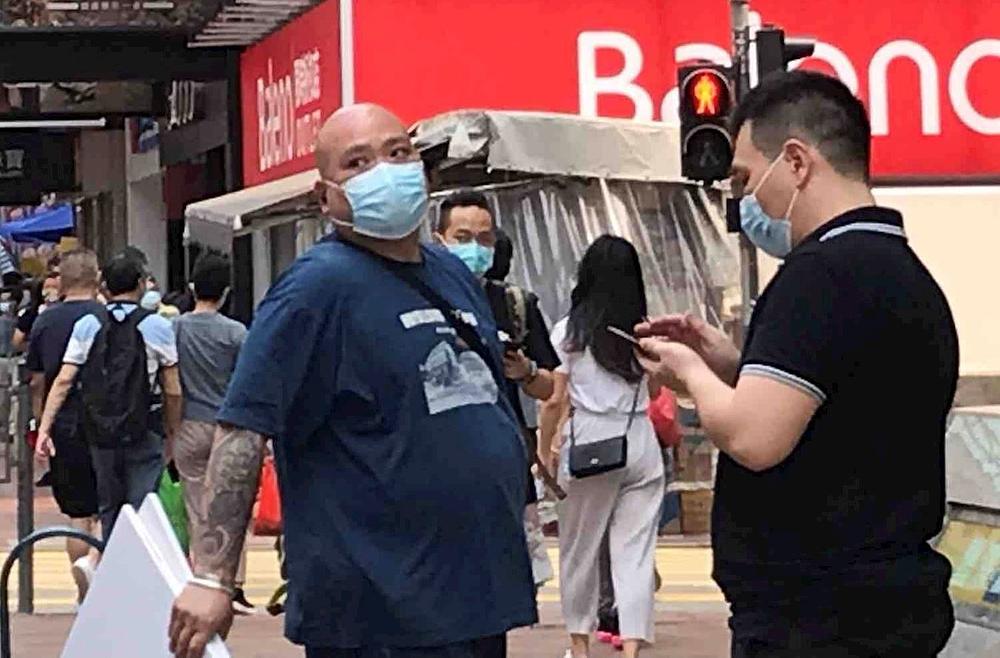 Dvojica su muškaraca i žena postavili transparente koji ocrnjuju Falun Gong pored uništenog Dafa štanda u ulici Argyle, Mong Kok, a jedan od njih je bio ćelavi čovjek s tetovažama na tijelu. 