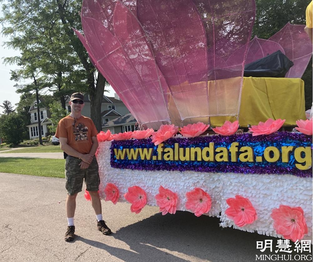 Joseph Brandon, koji se dobrovoljno prijavio za paradu, fotografisao se pored Falun Dafa splava.