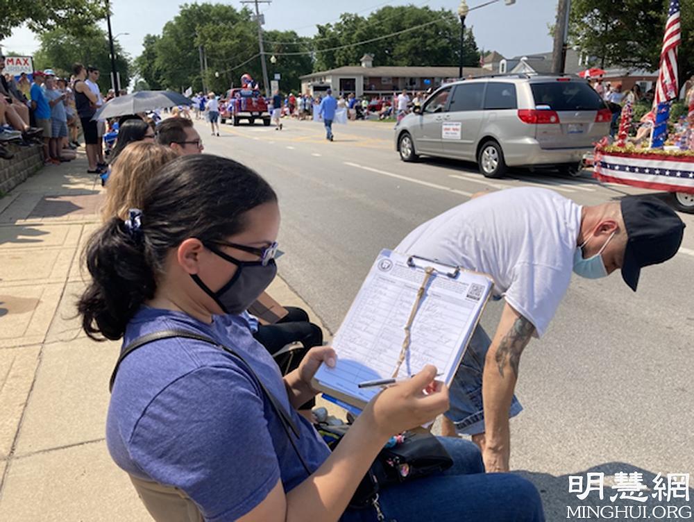 Posjetioci parade potpisuju peticiju kojom pozivaju na okončanje progona Falun Dafa.