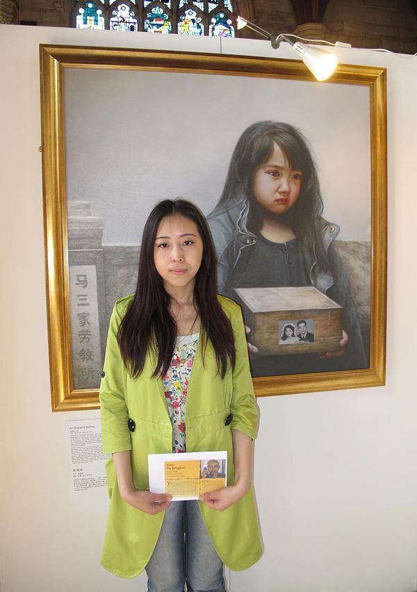 Gđa Yu Minghui stoji ispred slike "Suze siročeta" na Međunarodnoj izložbi umjetnost Istinitost, Dobrodušnost, Tolerancija u junu mjesecu 2013. godine, držeći razglednicu kojom podiže svijest o progonu svojih roditelja.
 
