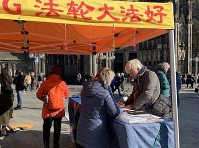 Čovjek ispred katedrale u Kölnu 5. marta 2022. godine potpisuje peticiju za zaustavljanje represija u Kini.