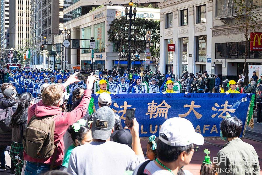Gledatelji su pozdravili Falun Dafa praktikante klicanjem, a mnogi su snimali glazbu Tian Guo Marching Banda 
