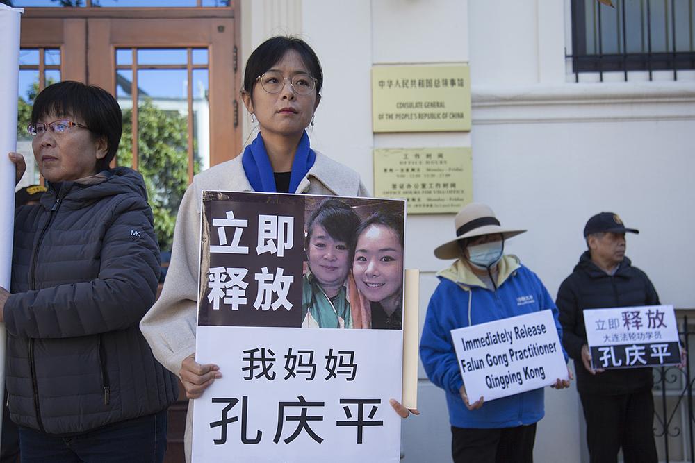  Gospođa Liu Zhitong drži fotografiju svoje majke. Na tabli piše: „Odmah pustite moju majku Kong Ćingping.