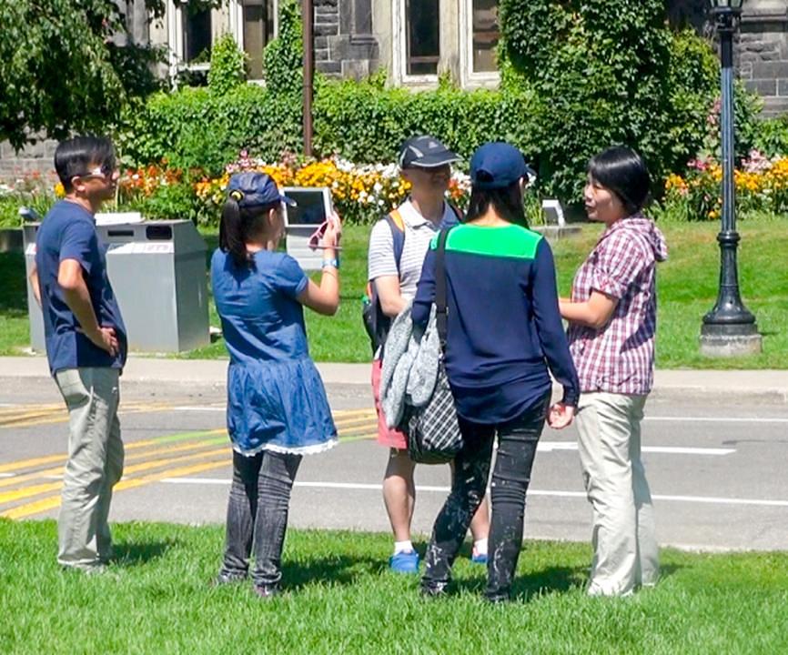 Turisti čitaju Falun Gong plakate i razgovaraju s praktikantima 