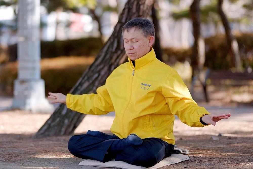 Gosp. Lee čita *Zhuan Falun* i prakticira petu vježbu Falun Dafe, meditaciju.