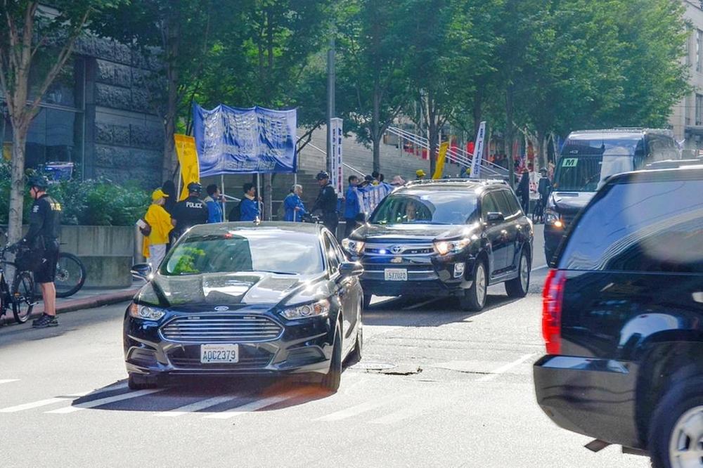 Povorka automobila prolazi pokraj Falun Gong plakata ispred Westina