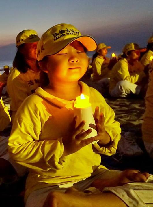 Praktikanti su održali bdijenje sa svijećama na plaži u znak sjećanja na kolege praktikante koji su mučeni do smrti u Kini zbog svojih uvjerenja.