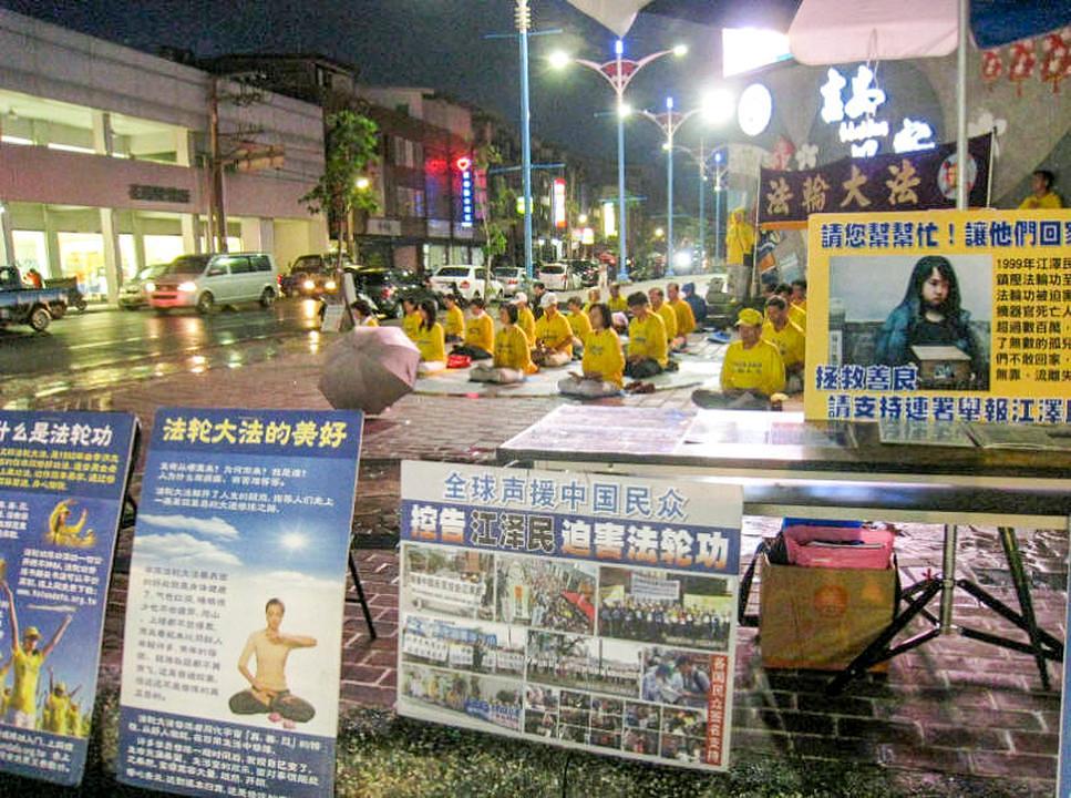Praktikanti pokazuju Falun Gong vježbe iza izloženih plakata 