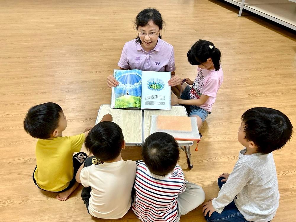 Učiteljica Weng čita djeci knjigu „Sveta knjiga s neba s plavim koricama.“