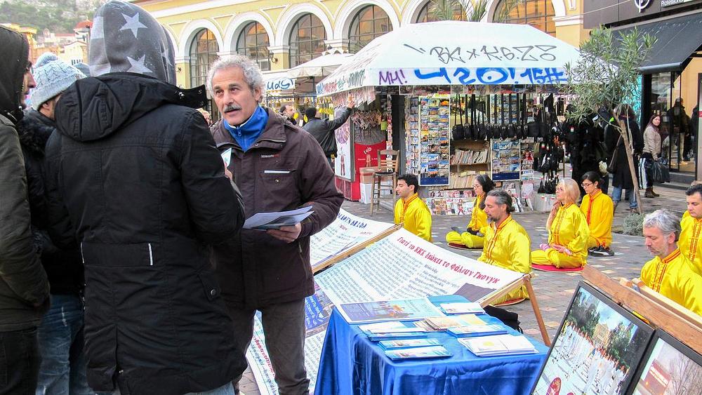Prolaznik na atinskoj željezničkoj stanici sluša praktikanta koji mu objašnjava Falun Dafa.