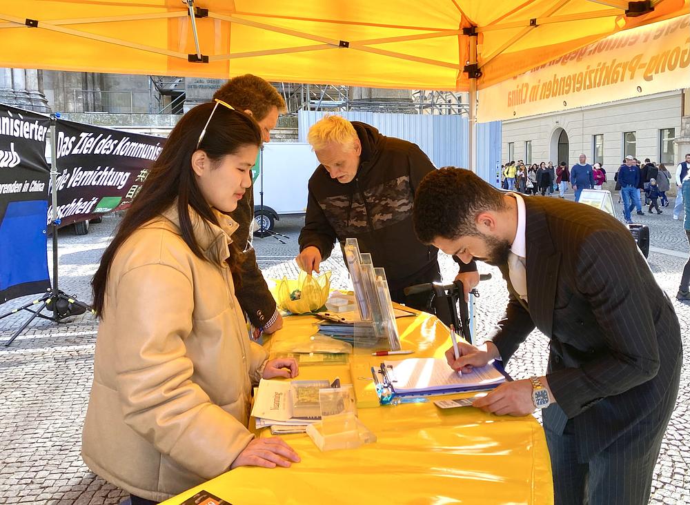  Ljudi razgovaraju s praktikantima na Odeonsplatzu i potpisuju peticiju kojom se poziva na prekid progona u Kini.