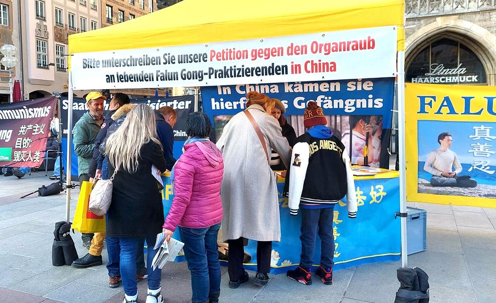 Ljudi potpisuju peticiju tokom događaja na Marienplatzu. 