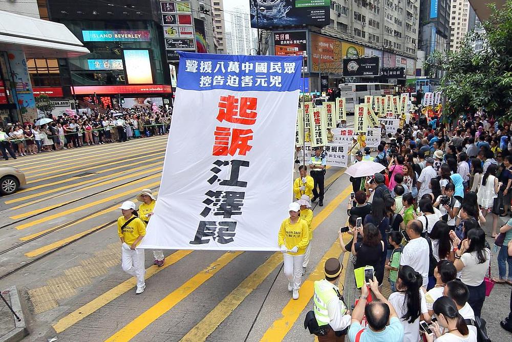 Parada u Hong Kongu 18. jula 2015. godine. Na velikom plakatu piše: „Podržimo 80.000 Kineza koji su tužili Jianga.“ Veliki znakovi znače: „Tužite Jiang Zemina“.