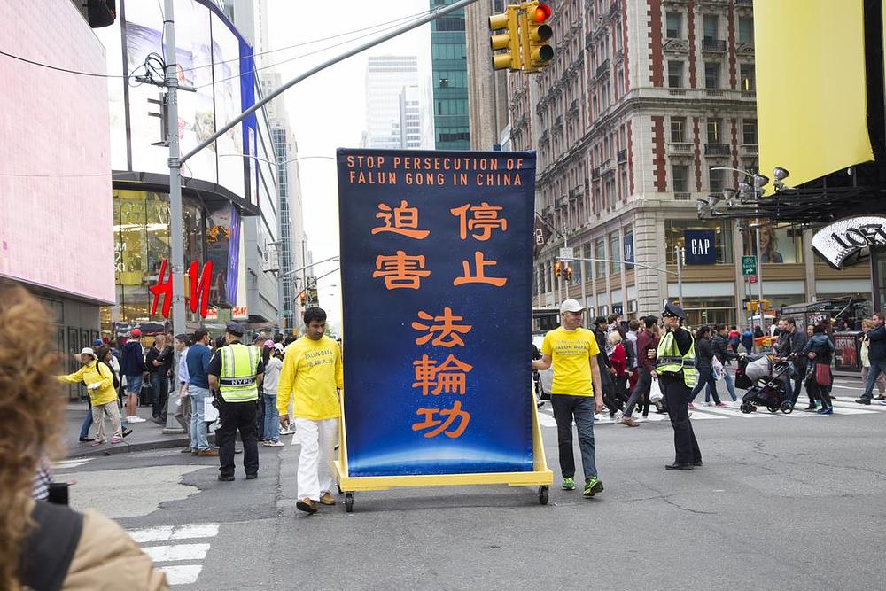 Praktikanti marširaju noseći veliki transparent sa natpisom: „Zaustavite progon Falun Gonga u Kini“