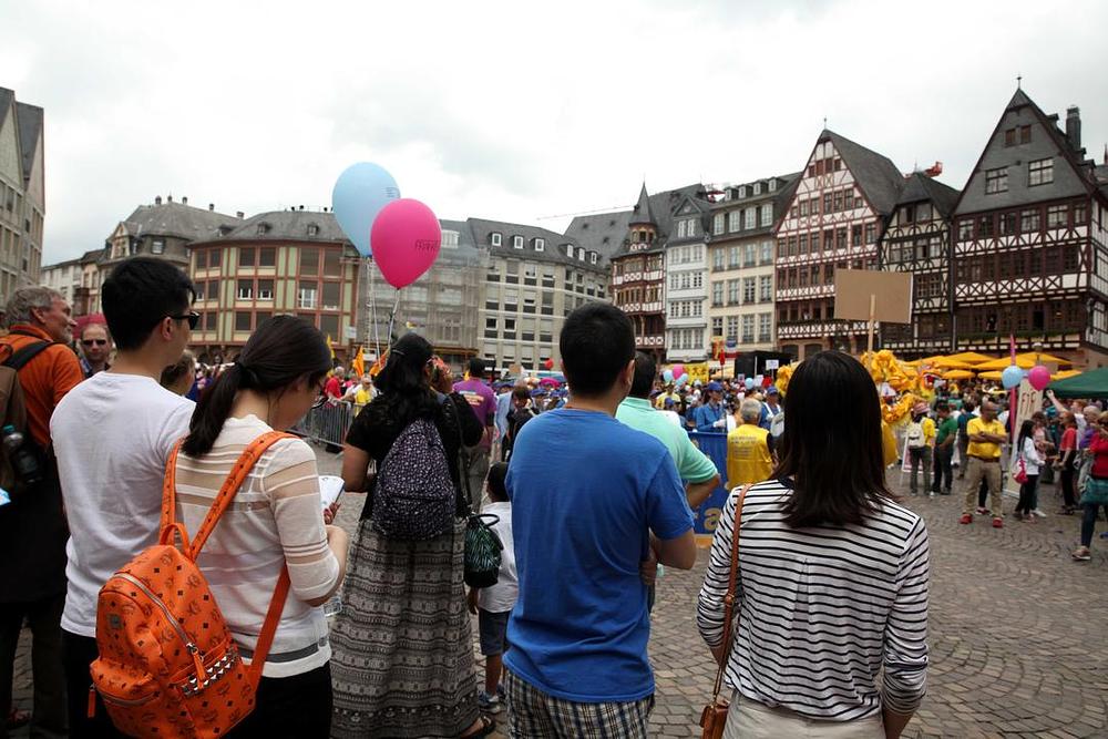 Kineski turisti gledaju nastup Falun Dafa grupe 