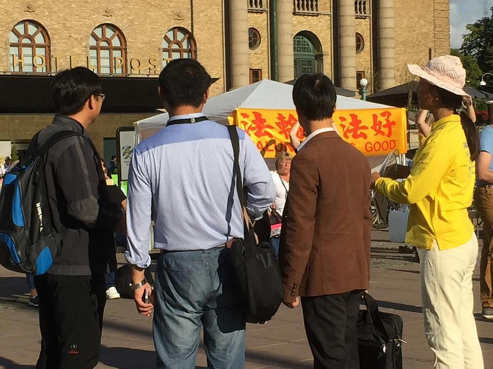 Kineski turisti zastaju kako bi gledali Falun Gong aktivnosti. 