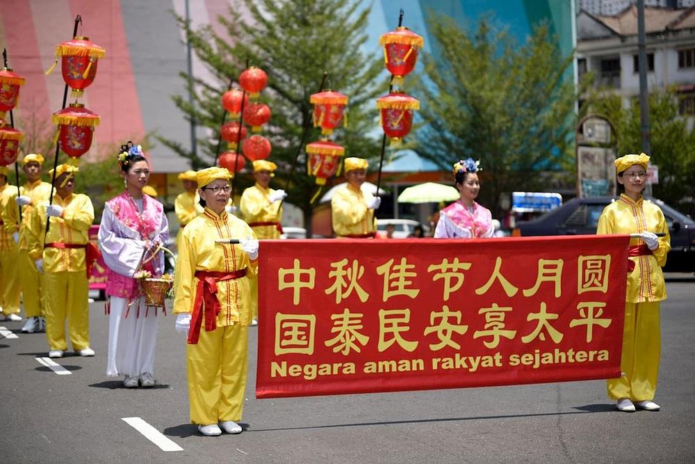 Mimohod praktikanata Falun Dafa. Na transparentu je napisano na kineskom i malezijskom jeziku: „Želimo napredak zemlje i miroljubivo društvo.“ 