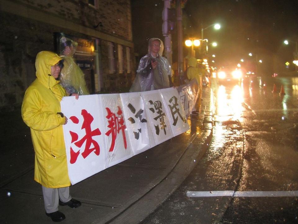 Praktikanti Falun Gonga drže istaknute transparente na kiši ispred Kanadskog istorisjkog muzeja, u očekivanju povorke automobila sa premijerom Lijem, nakon večere sa premijerom Trudeaouom.      