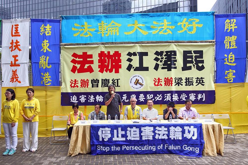 Veliki transparent u sredini nosi natpis (od vrha prema dnu) „Falun Dafa je dobar“ i „Izvedite Jiang Zemina pred lice pravde“. Jiang Zemin je bivši komunistički lider koji je 1999. godine pokrenuo progon Falun Gonga i lično njime rukovodio.