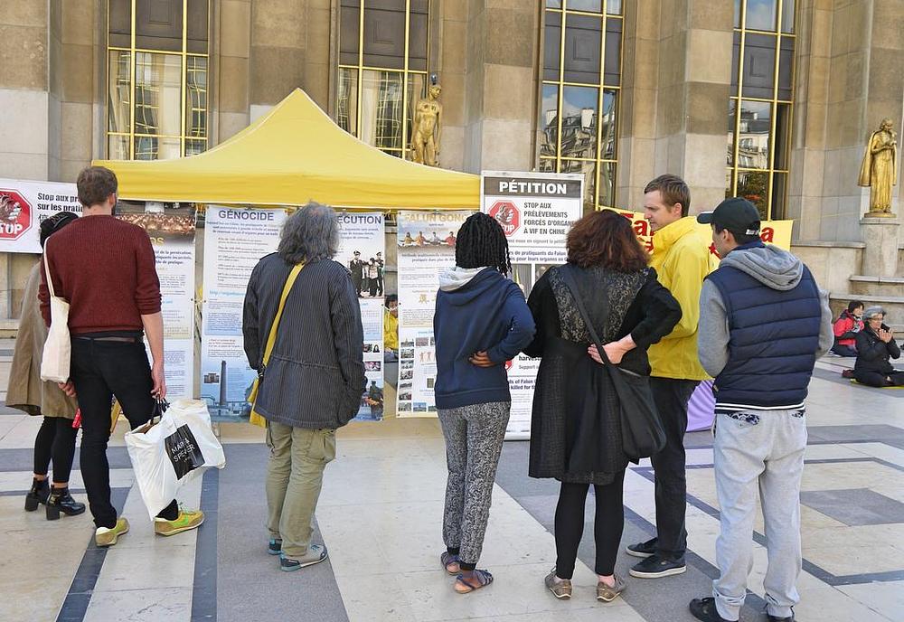 Prolaznici čitaju plakate i saznaju za Falun Gong i progon u Kini.