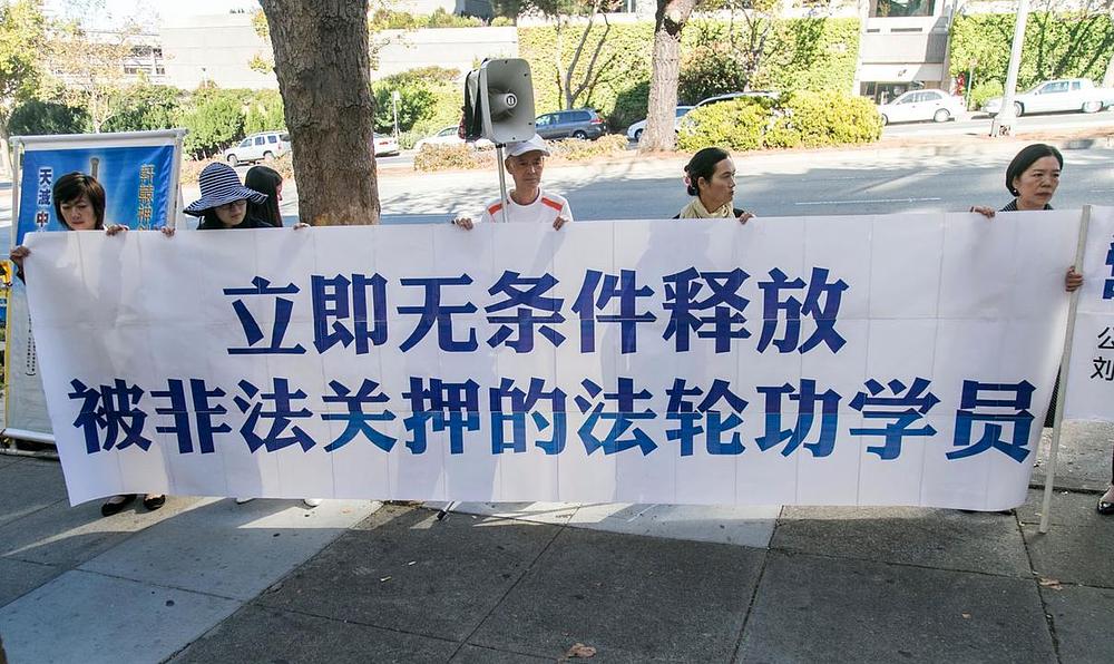 Na transparentu piše „Odmah oslobodite uhapšene praktikante Falun Gonga“ 