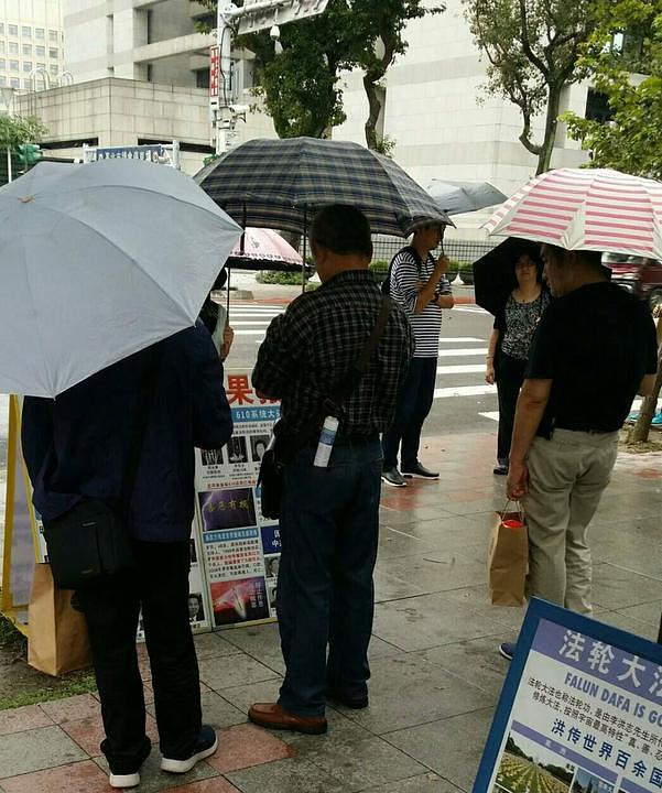 Turisti iz Kine proučavaju Falun Gong informativne materijale
