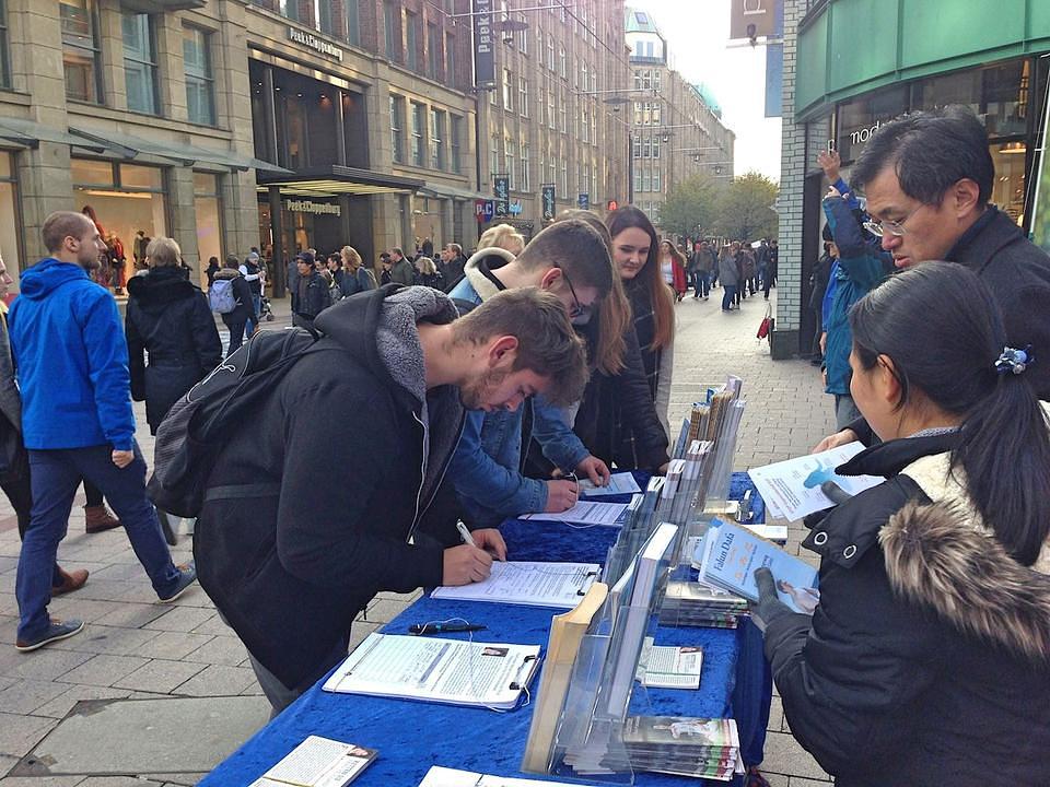Prolaznici potpisuju peticiju i tako osuđuju progon Falun Dafa. 