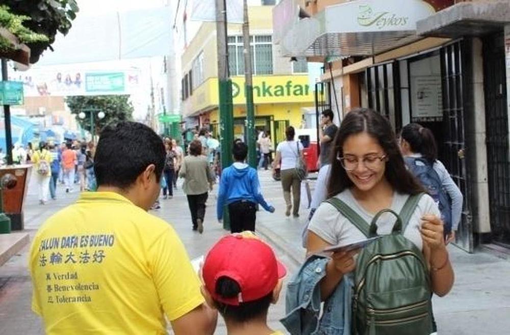 Djevojka uzima Falun Gong letak od praktikanta (u žutoj majici). 