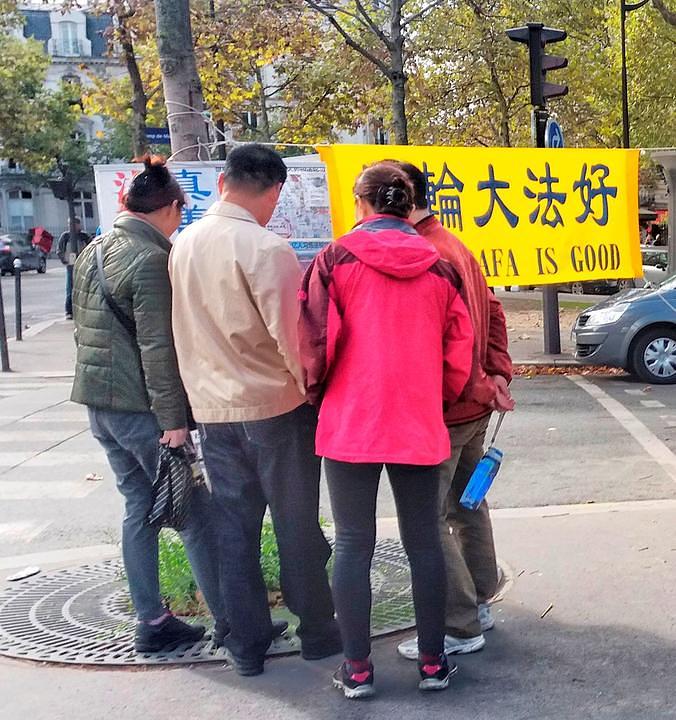 Kineski turisti čitaju plakate praktikanata Falun Gonga u blizini Eiffelovog tornja. 