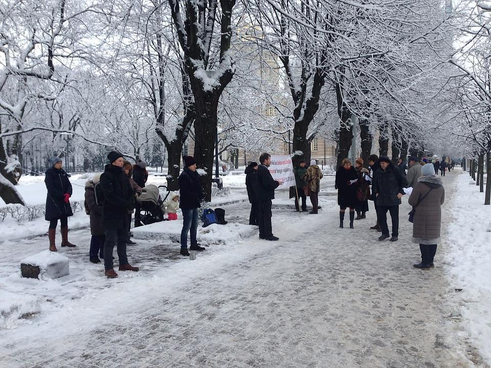 Prolaznici čitaju praktikantske plakate i posmatraju izvođenje Falun Gong vježbi.
