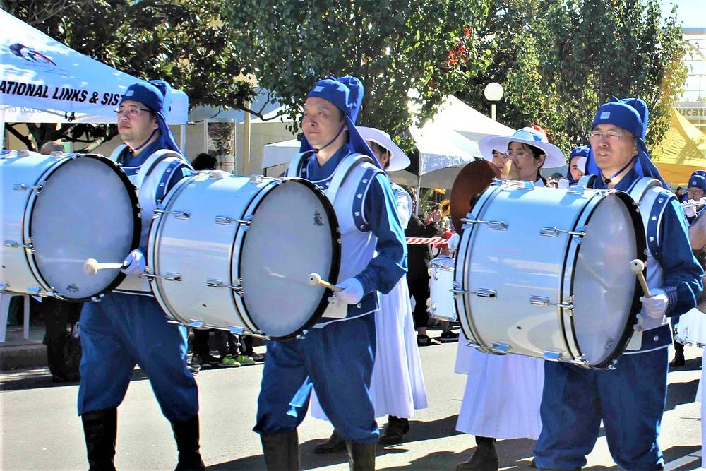 Henry (na slici drugi slijeva) svira bas bubanj u Tian Guo Marching Bandu, nakon što je vratio svoje zdravlje prakticirajući Falun Dafa.